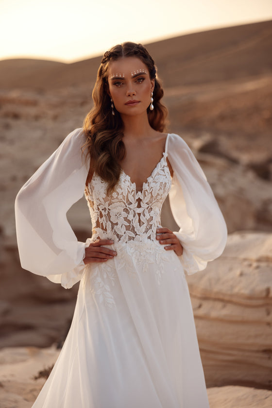 L’abito da sposa Judith presenta un corpetto in pizzo e maniche leggere in chiffon, per una sposa boho romantica.