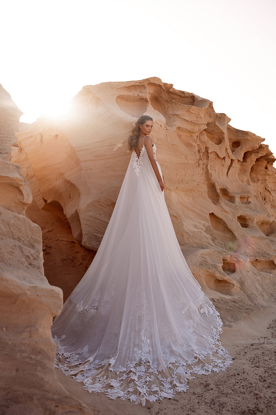 Cappa da sposa Malika trasparente, con applicazioni floreali e corpetto in pizzo effetto illusion, per uno stile romantico contemporaneo.