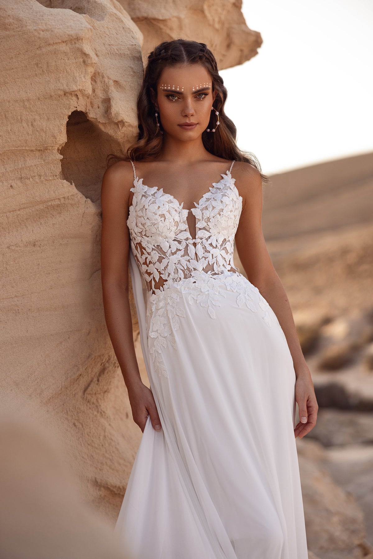 L’abito da sposa Malika mostra un raffinato strascico in pizzo a foglie, per un matrimonio boho da fiaba.