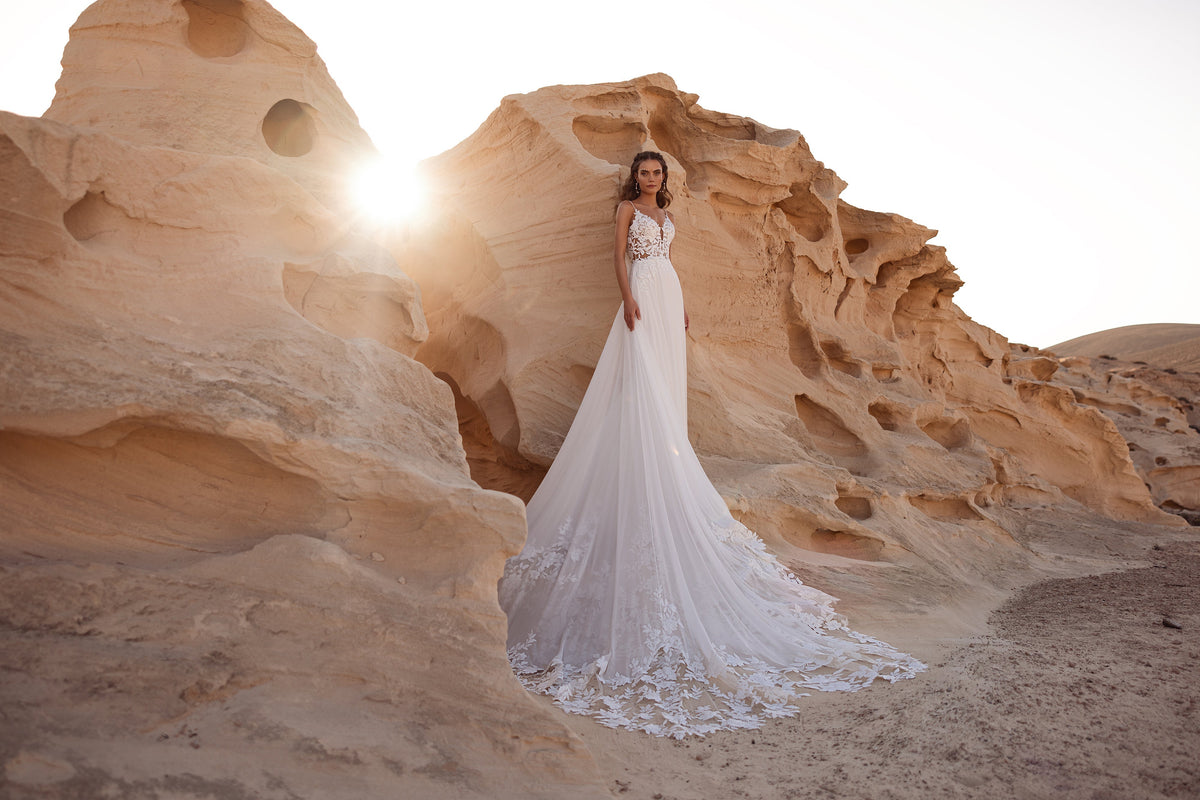 L’abito da sposa Malika presenta uno scollo a cuore e un corpetto in pizzo trasparente, per un look boho sensuale.