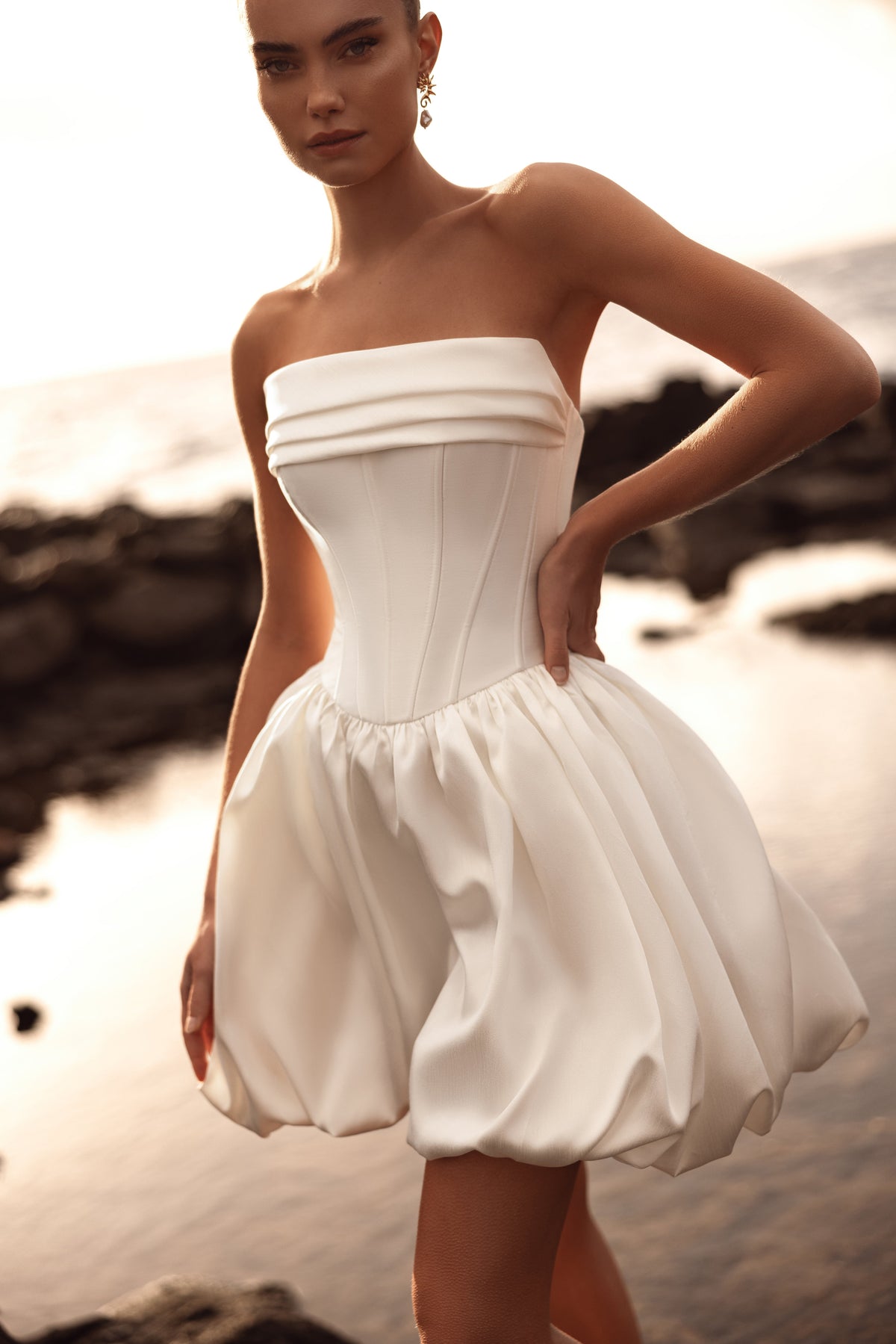 L’abito da sposa corto Martini, con corsetto bustier strutturato e gonna a palloncino, è una scelta contemporanea e raffinata per una sposa attenta allo stile.