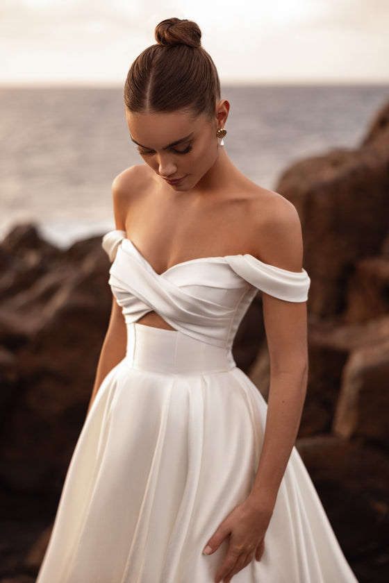 Abito da sposa Mellisandre con corsetto e scollo drappeggiato a spalle scoperte, che unisce stile contemporaneo e romanticismo senza tempo.