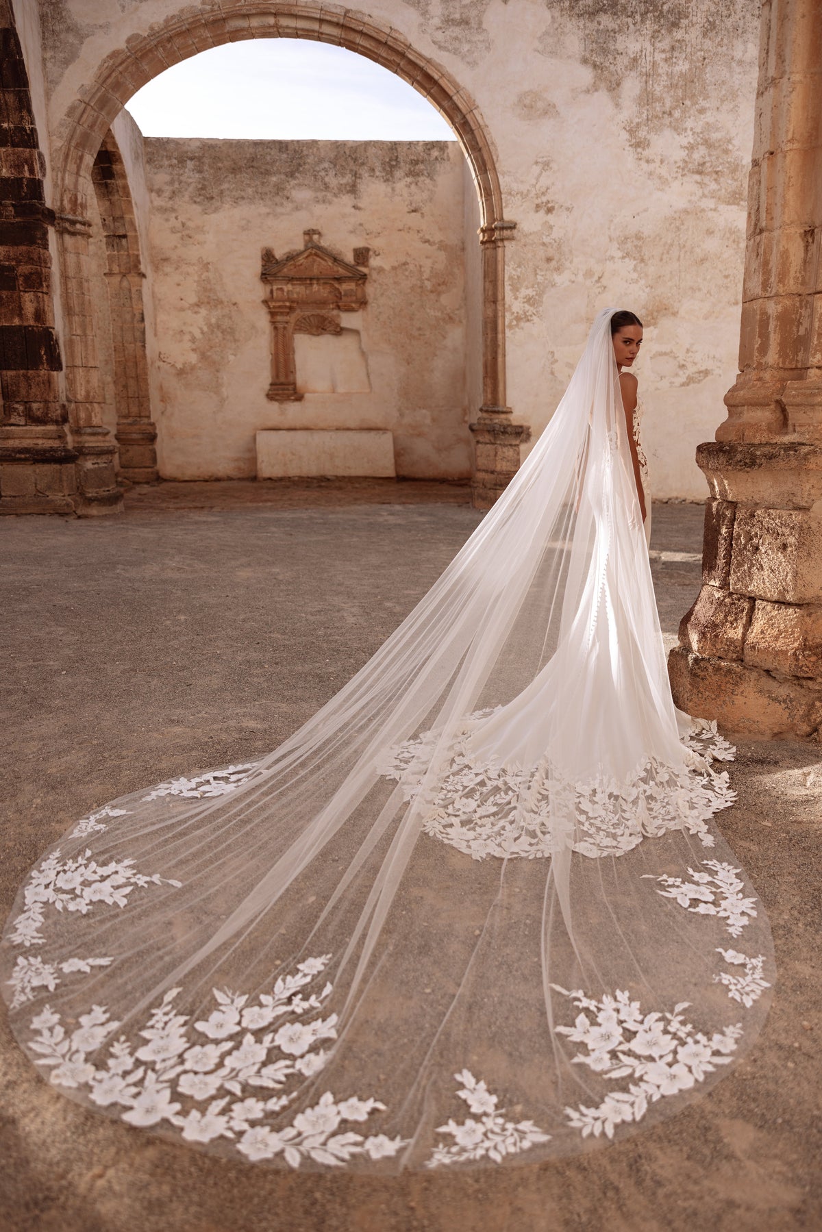 Velo da sposa cattedrale Munira con applicazioni di pizzo floreale, per un look scenografico tra rovine storiche.