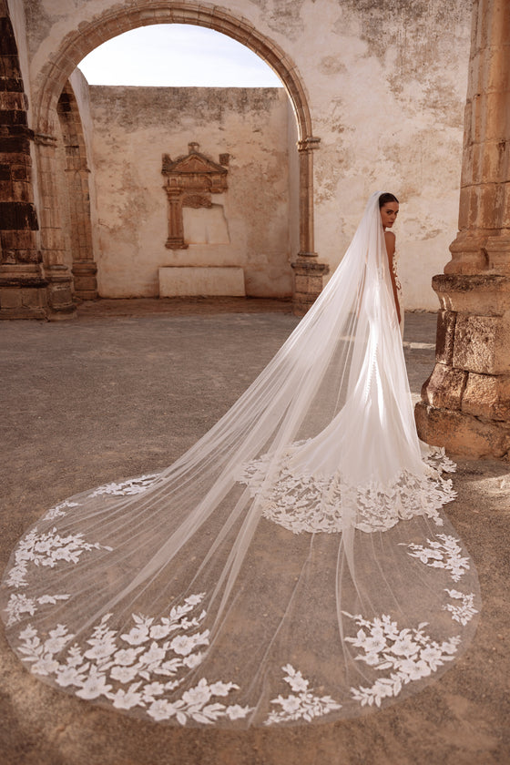Velo da sposa cattedrale Munira con applicazioni di pizzo floreale, per un look scenografico tra rovine storiche.