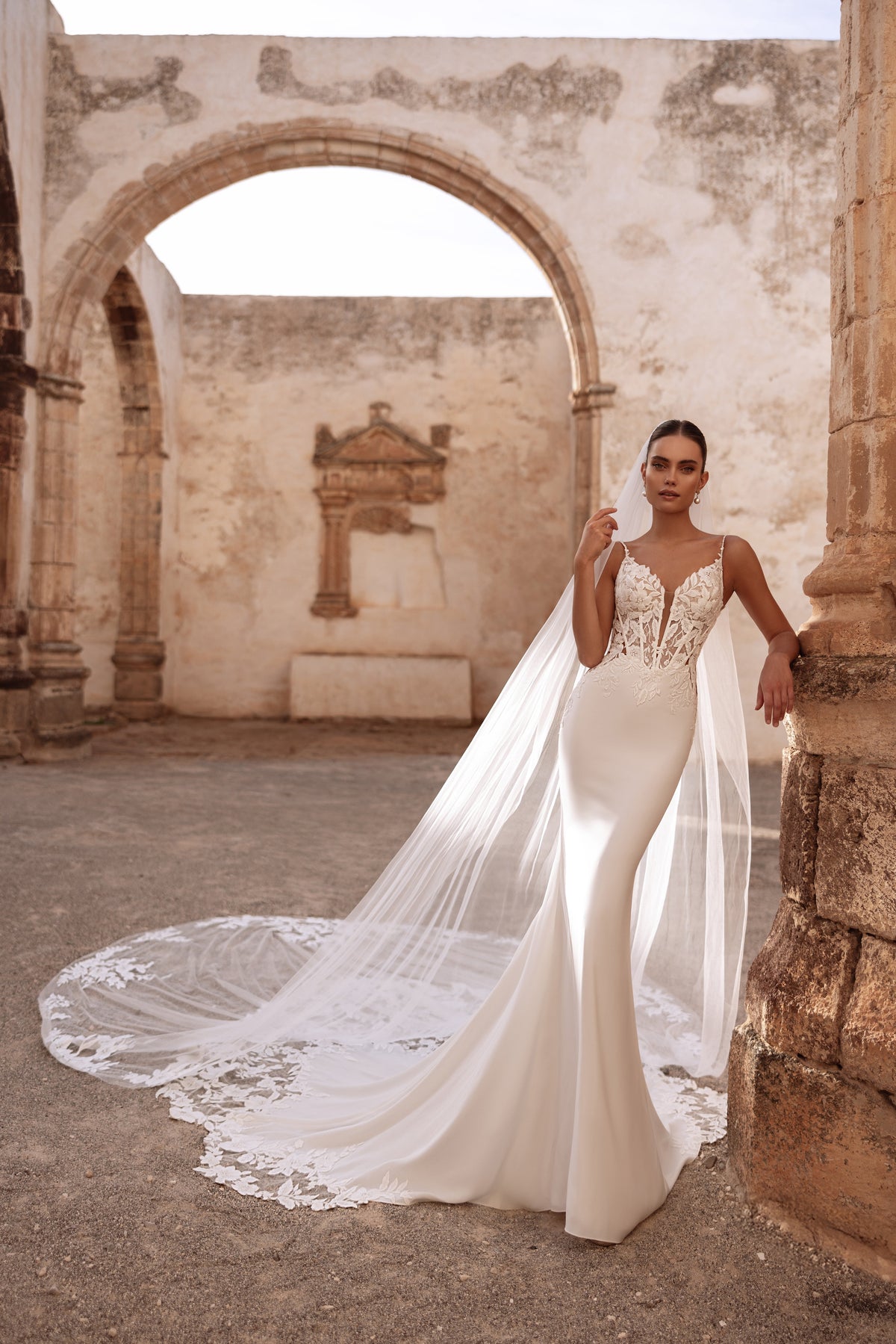 Il velo da sposa Munira, con applicazioni di pizzo, completa l’abito con un accento romantico ed etereo.