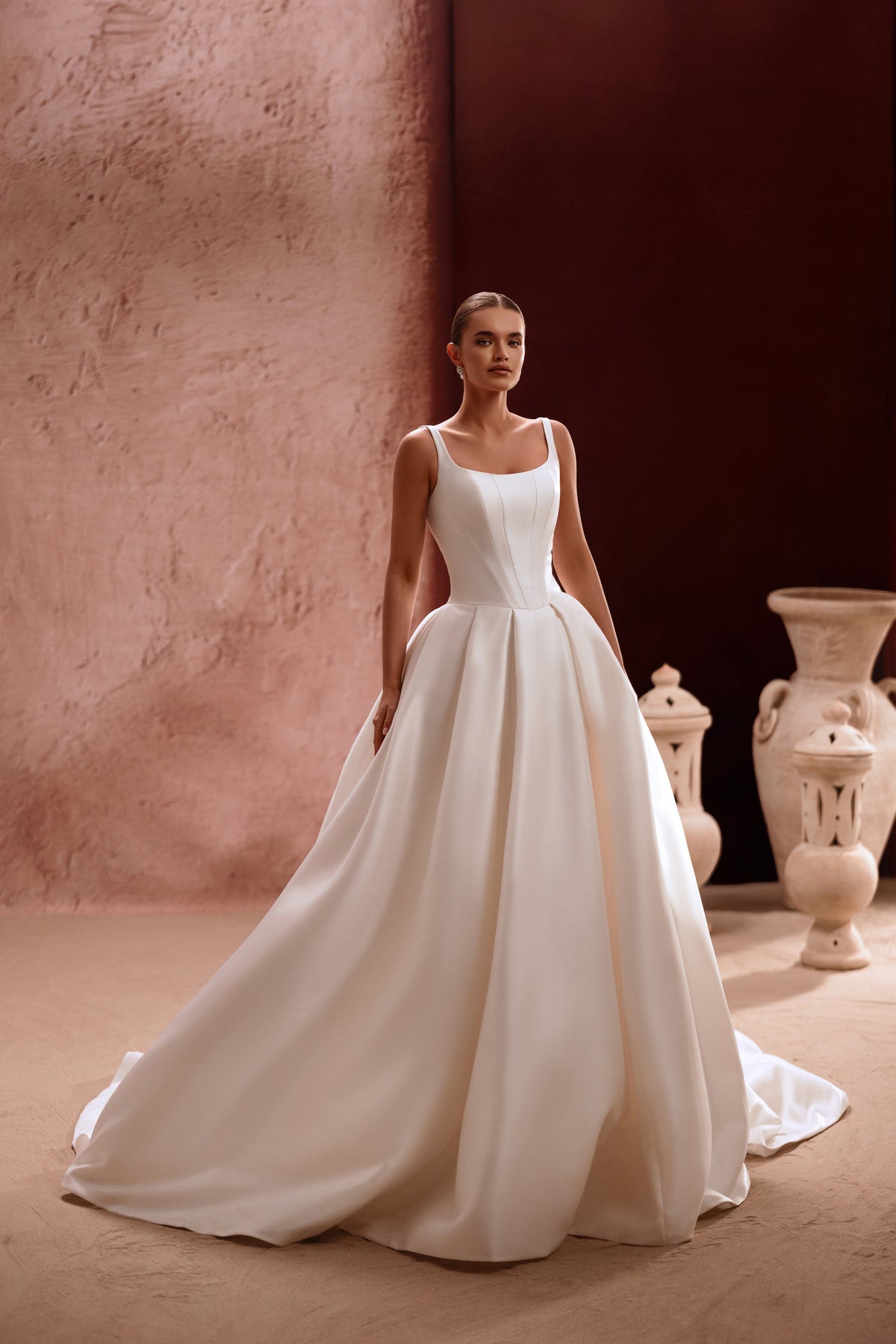 L’abito da sposa Nicolette, con scollo quadrato e corpetto strutturato, valorizza la figura con un’eleganza disinvolta.