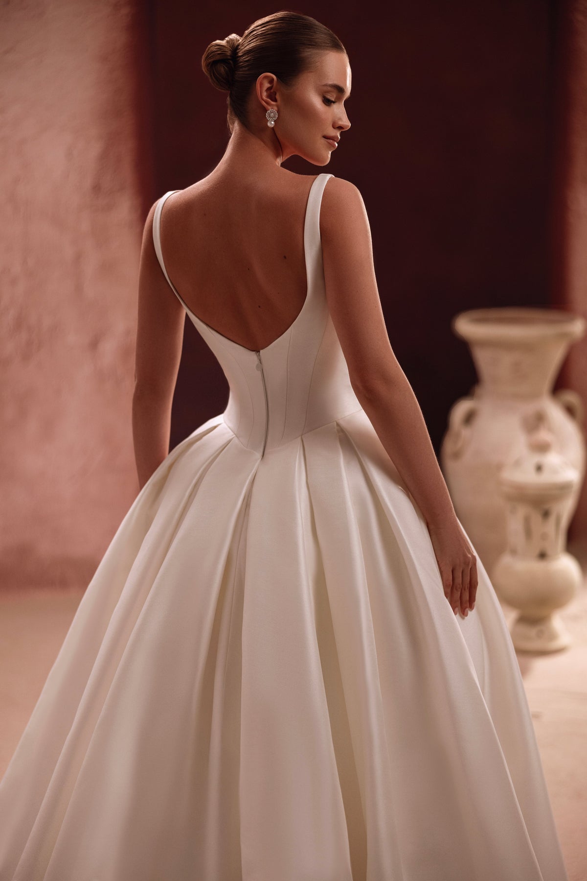 L’abito da sposa Nicolette, con un velo in tulle decorato da fiori di grandi dimensioni, aggiunge un accento artistico a un look contemporaneo.