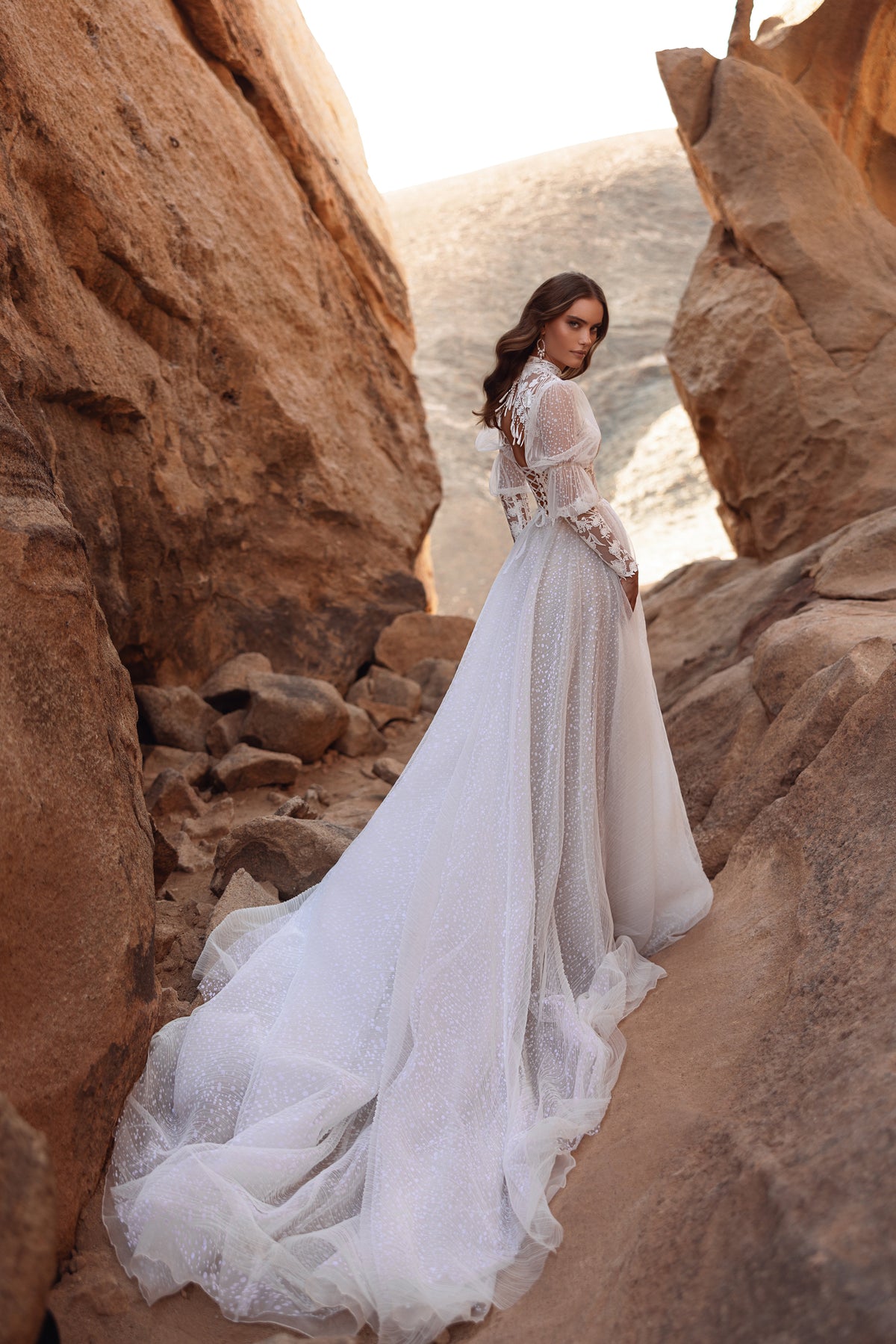 L’abito da sposa Oasis, con scollo alto e maniche lunghe in pizzo, unisce raffinatezza contemporanea e romanticismo senza tempo.
