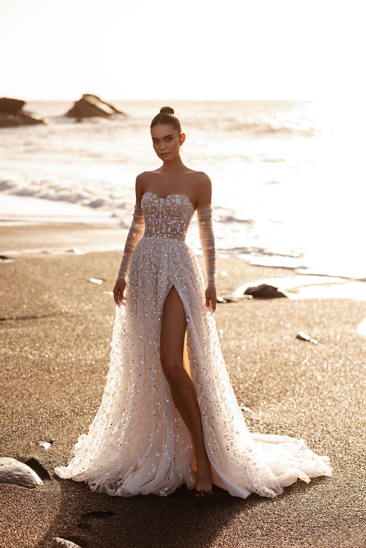 L’abito da sposa Reem, con corsetto di paillettes e lungo strascico, affascina con la trama floreale 3D e i romantici scintillii in riva al mare.