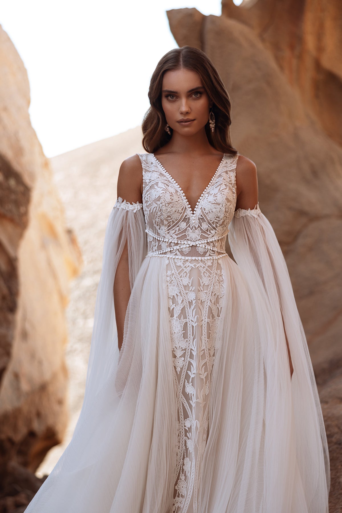 L’abito da sposa Salome, con spalle scoperte e lunghe maniche in tulle, unisce carattere boho e romantici dettagli in pizzo.