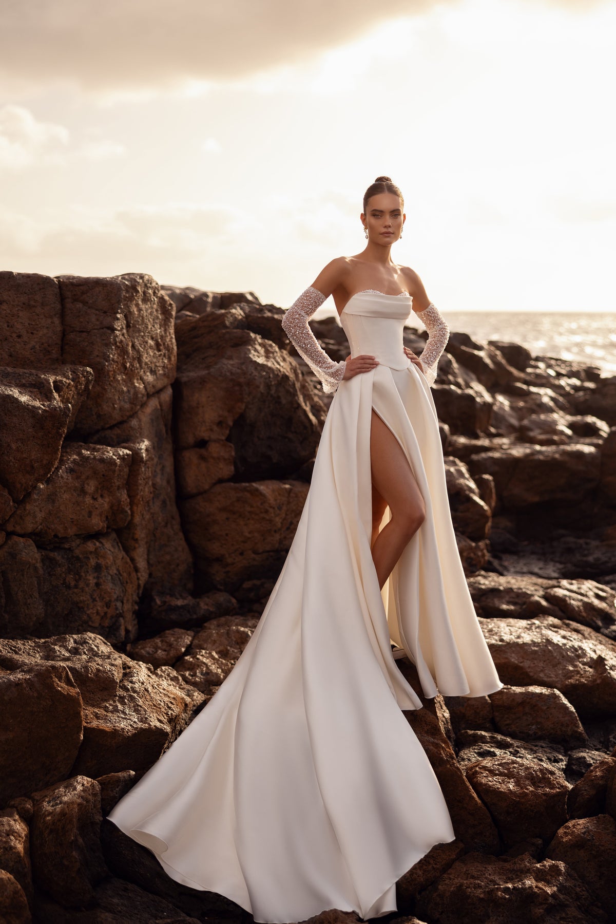 L’abito da sposa Sarabi, con corsetto strutturato e guanti decorati con perle, sottolinea un’eleganza femminile e preziosa.