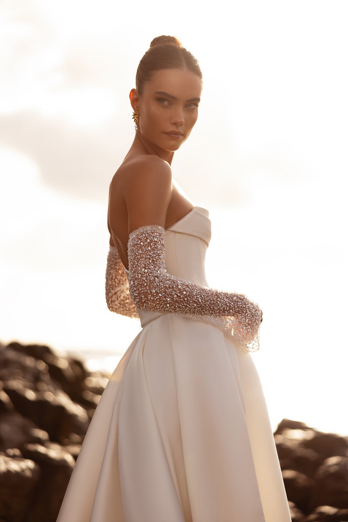 L’abito da sposa Sarabi, con schiena scoperta e ampio strascico, unisce eleganza senza tempo e minimalismo contemporaneo.
