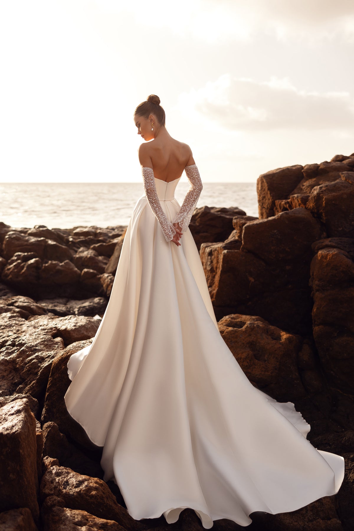 L’abito da sposa Sarabi senza spalline, abbinato a guanti impreziositi di perle, crea un look prezioso e glamour.