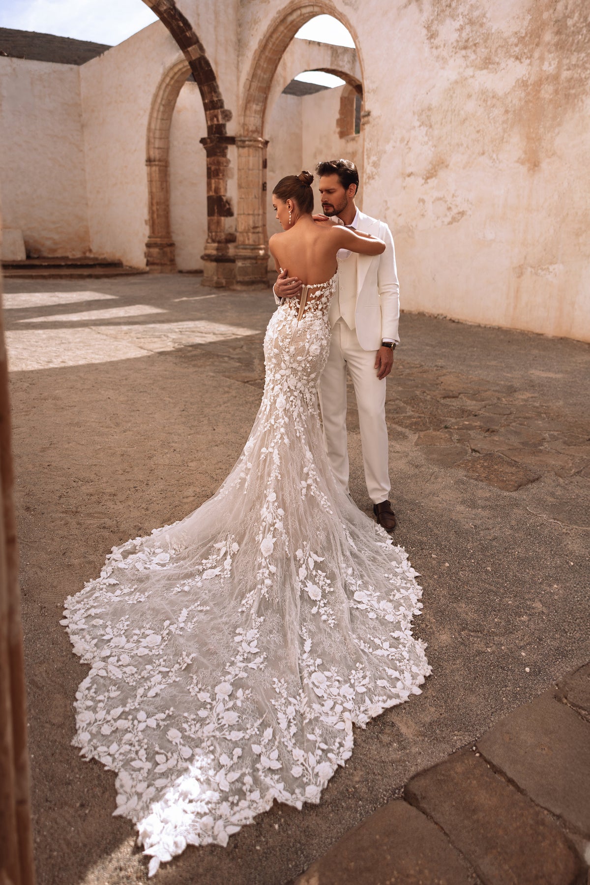 L’abito da sposa Sarifa a sirena, con corpetto a corsetto e ricami in pizzo floreale, valorizza la figura della sposa.