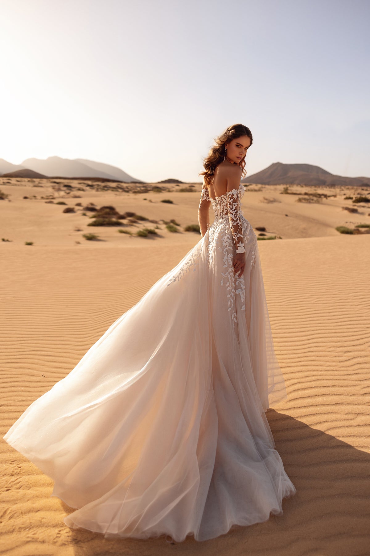 L’abito da sposa Tamara, con maniche in pizzo che lasciano scoperte le spalle, valorizza l’eleganza e il carattere romantico della sposa.