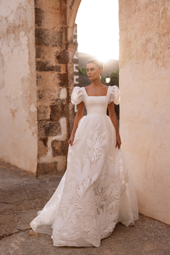 L’abito da sposa Vanilla, con scollo quadrato e maniche a sbuffo, accompagna un momento di gioia della sposa.