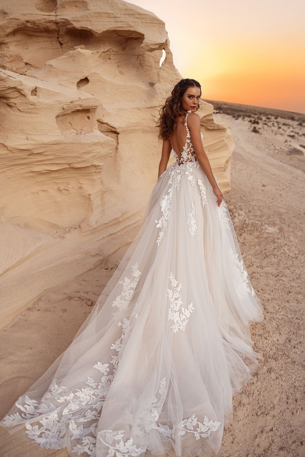 L’abito da sposa Zafira, con schiena scoperta e lungo strascico in tulle decorato con applicazioni di pizzo floreale 3D.